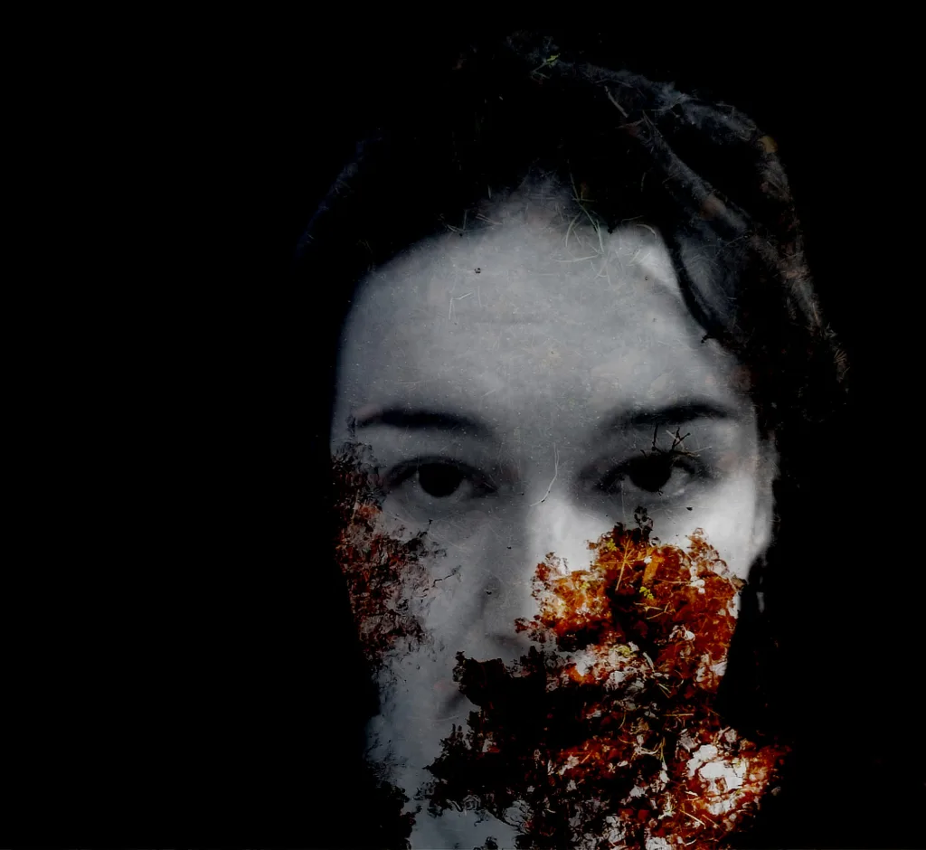 Photograph from the series Behind the Looking Glass by Anna Wiksten: a woman with fall leaves over her mouth.