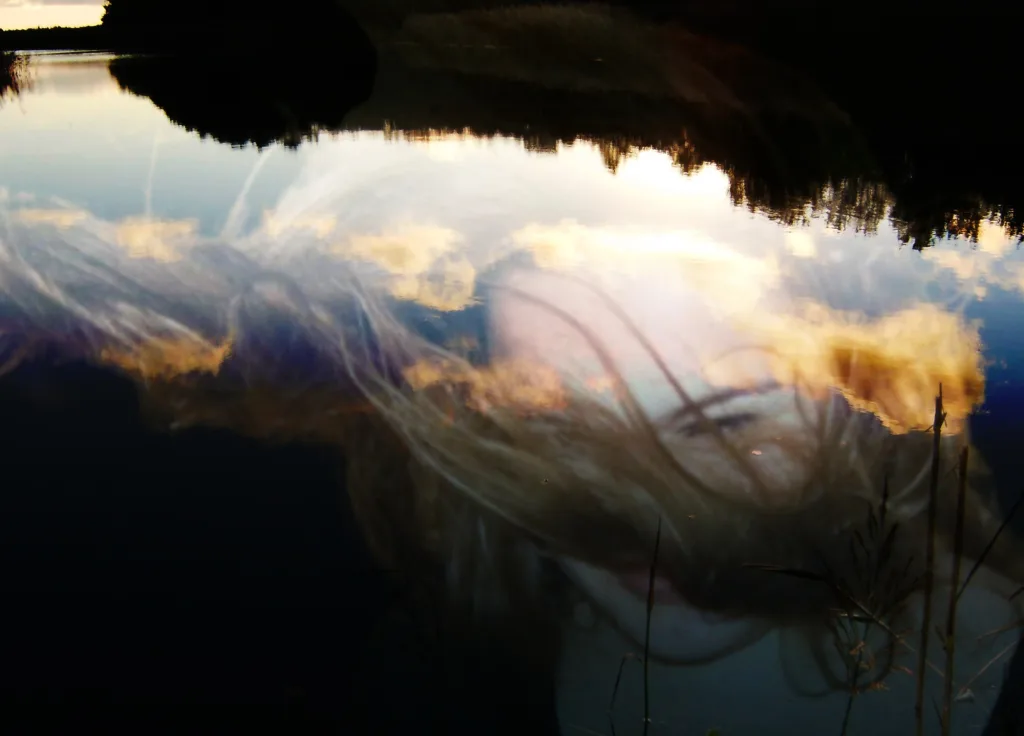 Photograph from the series Behind the Looking Glass by Anna Wiksten: a woman sinking into water.