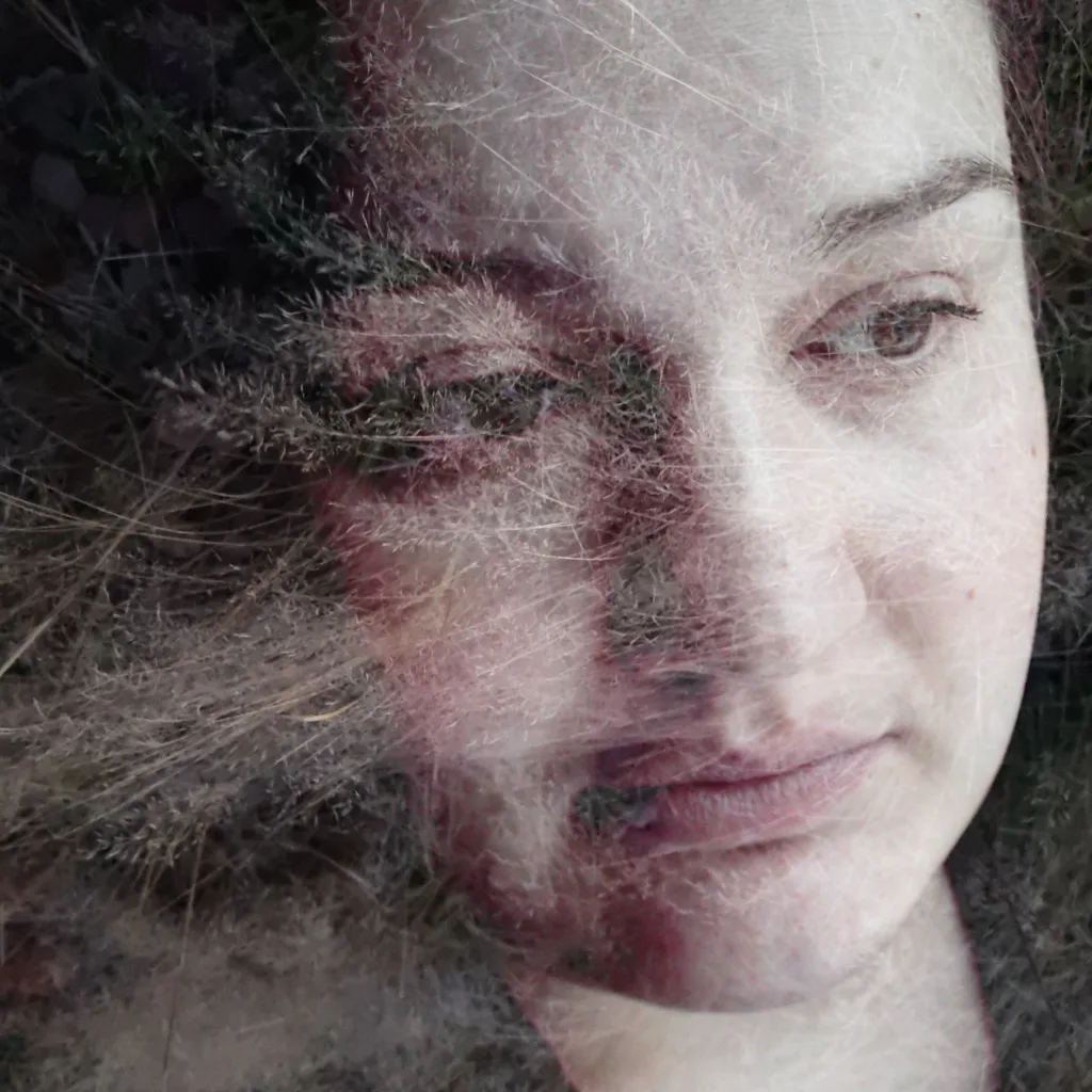 Photograph from the series Behind the Looking Glass by Anna Wiksten: closeup of a woman with dried blades of grass.