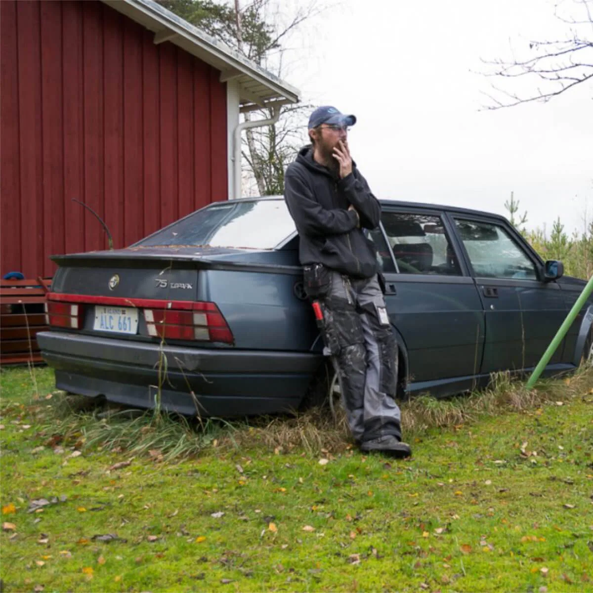 Fotografi av Anna Wiksten: man som står lutad mot en bil och röker.